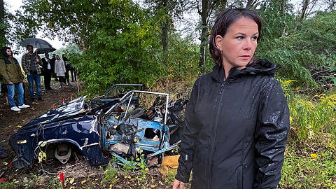Die deutsche Außenministerin Annalena Baerbock (Bündnis 90/Die Grünen) besichtigt ein von Deutschland gefördertes Minenräumprojekt in der Nähe von Kiew. Das Auto im Hintergrund ist durch eine Mine zerstört worden.