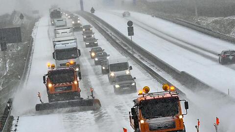 Zwei Räumfahrzeuge des Winterdienstes fahren auf der Autobahn A12 in Brandenburg.