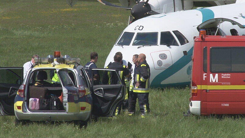 Mitarbeiter des Flughafens in München betrachten die Maschine der italienischen Fluggesellschaft, die am Donnerstag auf dem Münchner Flughafen notlanden musste. Das Flugzeug mit 62 Menschen an Bord hatte kurz nach dem Start in Richtung Venedig umdrehen müssen, weil sich Rauch in der Kabine entwickelt hatte. Bei der Landung wurden fünf Personen leicht verletzt, die Maschine kam neben der Landebahn zum Stehen.
