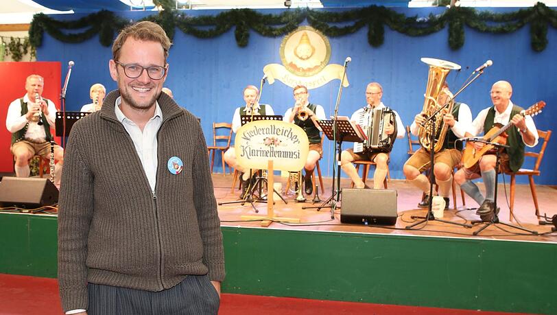 Martin Jonas, der Musik-Chef vom Herzkasperl-Festzelt: Im Hintergrund auf der Bühne spielen Musikanten zur Mittagswiesn auf. Martin Jonas, der Musik-Chef vom Herzkasperl-Festzelt: Im Hintergrund auf der Bühne spielen Musikanten zur Mittagswiesn auf.