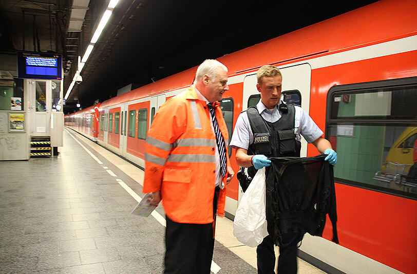 Erich Brzosa, der Leiter der DB Netz AG für den Großraum München (l.) mit einem Polizeibeamten, der die Jacke in der Hand hält, die für die Stammstreckensperrung verantwortlich ist.