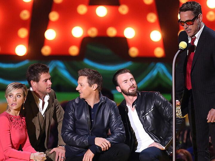 Die Darsteller aus "The Avengers" knien vor Robert Downey Jr. (v.li.: Scarlett Johansson, Chris Hemsworth, Jeremy Renner und Chris Evans)