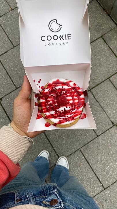 Der "Raspberry White Chocolate-Cookie" ist mit reichlich Vanille-Frosting und Himbeerpüree verziert. Der "Raspberry White Chocolate-Cookie" ist mit reichlich Vanille-Frosting und Himbeerpüree verziert.