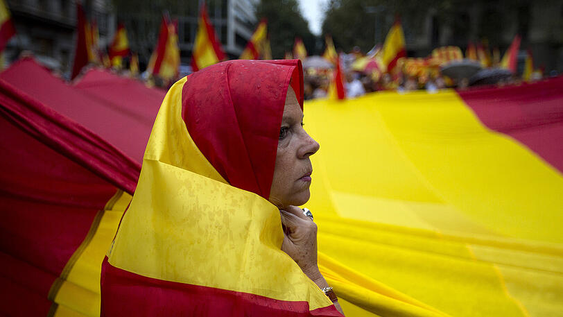 Eine Demonstrantin hilft in Barcelona bei einer Demonstration gegen die Unabhängigkeit Kataloniens eine riesige spanische Flagge zu tragen.