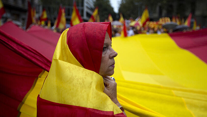 Eine Demonstrantin hilft in Barcelona bei einer Demonstration gegen die Unabhängigkeit Kataloniens eine riesige spanische Flagge zu tragen. Eine Demonstrantin hilft in Barcelona bei einer Demonstration gegen die Unabhängigkeit Kataloniens eine riesige spanische Flagge zu tragen.