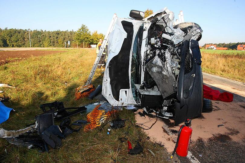 Das ausgebrannte Autowrack liegt am Fahrbahnrand. Nach einem Frontalzusammenstoß sind hier zwei Menschen gestorben, vier weitere wurden schwer und lebensgefährlich verletzt.