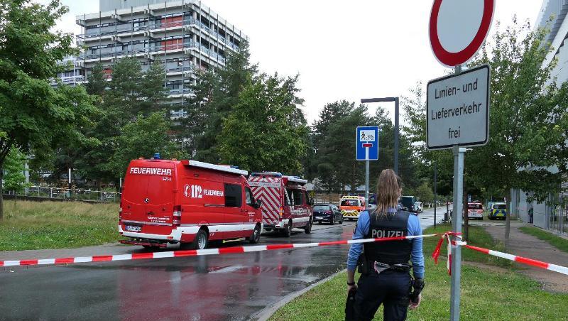 Eine Beamtin und Einsatzfahrzeuge der Feuerwehr auf dem Campus der TU Darmstadt.