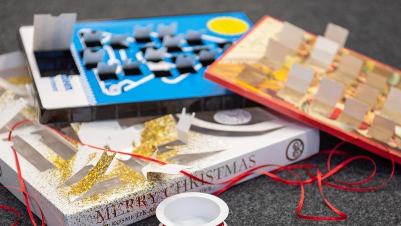 Leere Adventskalender liegen zusammen mit einer Rolle Geschenkband auf dem Boden. Leere Adventskalender liegen zusammen mit einer Rolle Geschenkband auf dem Boden.