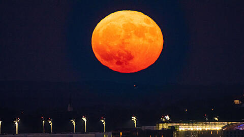 Der Vollmond geht am Abend über dem Flughafen München im Hallbergmoos auf.