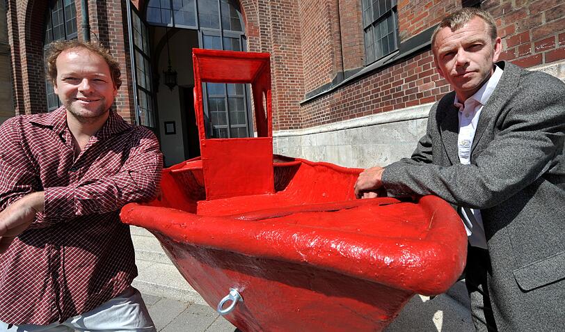 Lust am Sinnlosen: Die Münchner Künstler Thomas Huber (links) und Wolfgang Aichner mit ihrem knallroten Plastikboot in München vor der Abreise in die Alpen.