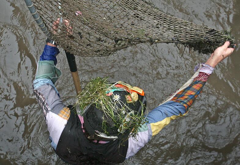 Ein Teilnehmer des Memminger Fischertages steht am Samstag (23.07.2011) mit seinem Fangnetz, dem sogenannten Bären, im Stadtbach von Memmingen (Schwaben).