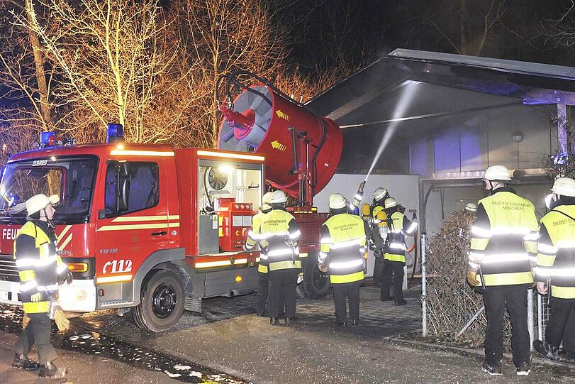 Die Feuerwehr versucht, den Brand im Mülltonnenhaus zu löschen.