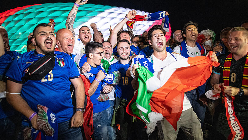 Fans der italienischen Nationalmannschaft feiern den Sieg vor dem beleuchteten Stadion. Fans der italienischen Nationalmannschaft feiern den Sieg vor dem beleuchteten Stadion.