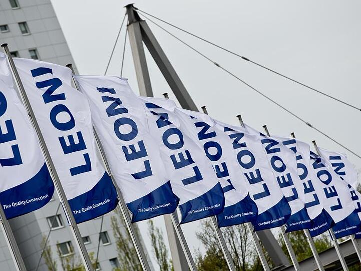 Fahnen mit dem Logo des Kabel-Herstellers Leoni AG wehen im Wind. Foto: Daniel Karmann/dpa/Symbolbild