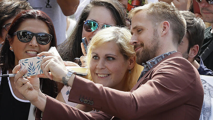 Der Schauspieler Ryan Gosling macht ein Selfie mit einer Frau, als er zum Photocall für den Film "First Man"kommt.