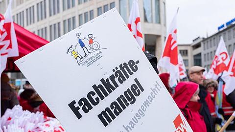 Menschen stehen während eines Protests mit Transparenten mit der Aufschrift "Fachkräftemangel". Foto: Peter Steffen/dpa/Archiv