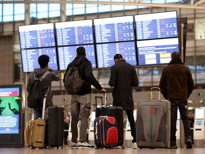 Fluggäste stehen vor einer Anzeigetafel im Terminal 1 des Flughafens Hamburg.