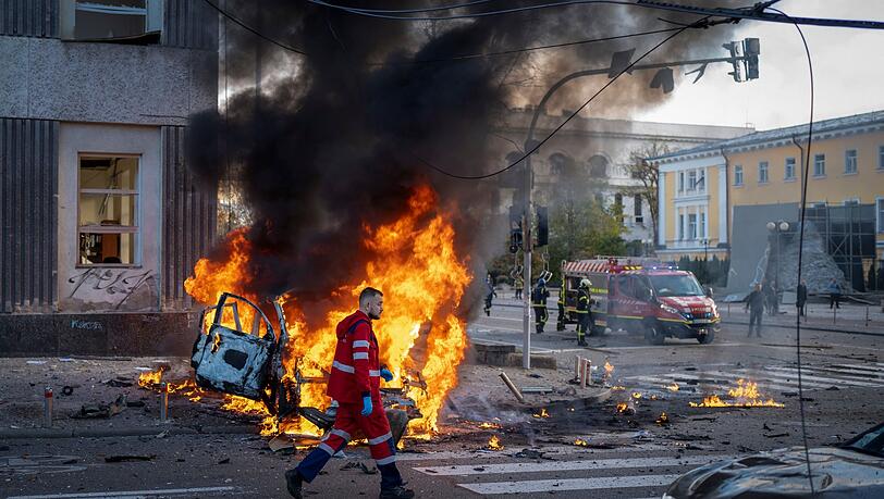 Ein Sanitäter geht nach einem russischen Angriff auf Kiew an einem brennenden Auto vorbei. Ein Sanitäter geht nach einem russischen Angriff auf Kiew an einem brennenden Auto vorbei.