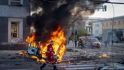 Ein Sanitäter geht nach einem russischen Angriff auf Kiew an einem brennenden Auto vorbei.