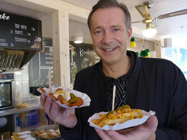 Sterne-Koch Alexander Herrmann steht mit Pommesschalen im einem Freibadkiosk. Foto: Gert-Dieter Meier/AHa-Effekt