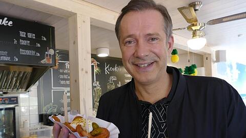 Sterne-Koch Alexander Herrmann steht mit Pommesschalen im einem Freibadkiosk. Foto: Gert-Dieter Meier/AHa-Effekt