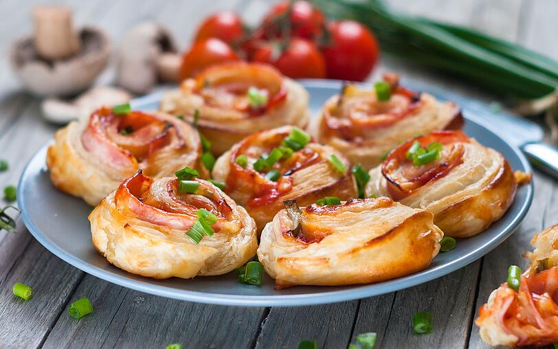 Etwas handlicher wird es mit Ofenschnecken: wie eine normale Pizza wird der Teig mit passierten Tomaten oder Tomatenmark bestrichen und belegt, beispielsweise mit Salami, K&auml;se, Mais, Pilzen oder Spinat. Nun wird der Teig fest zusammengerollt und in circa drei Zentimeter dicke Scheiben geschnitten. Legen Sie die Schnecken auf ein Backblech und backen das Fingerfood f&uuml;r 15 Minuten im Ofen.