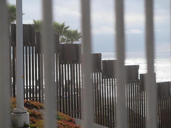 Durch einen Grenzzaun auf der US-Seite sind eine weitere Barriere und der Pazifikstrand zu sehen.