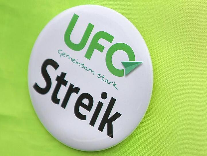 Ein Button der Flugbegleitergewerkschaft UFO ist auf hellgrünem Hintergrund zu sehen. Foto: Oliver Berg/dpa/Archivbild
