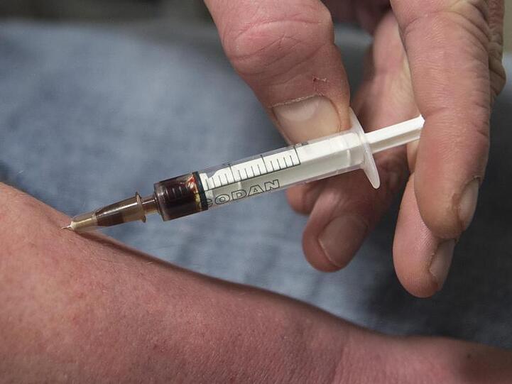 Jemand spritzt sich einen Schuss Heroin in den Unterarm. Foto: Boris Roessler/Archivbild