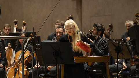 Kristi M&uuml;hling streicht mit dem Besen den Kannel, eine estnische Zither.