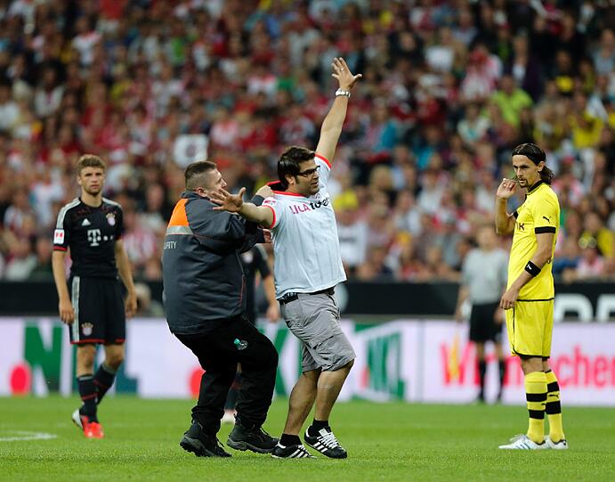 Er rennt in der 55. Minute auf den Platz und sorgt kurz für Aufsehen: Der Bayern-Fan und Flitzer wird von den Sicherheitskräften aber schnell gestellt.