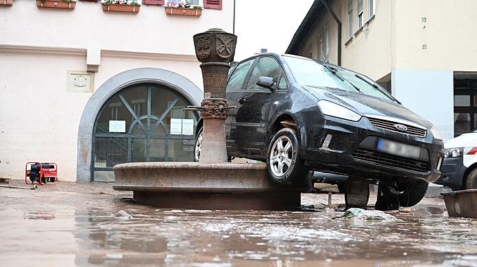 Auf einem Brunnen in Rudersberg hängt ein durch das Hochwasser weggespültes Auto. Auf einem Brunnen in Rudersberg hängt ein durch das Hochwasser weggespültes Auto.
