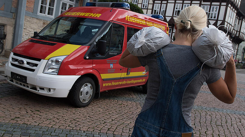 Eine Helferin in Wolfenbüttel trägt Sandsäcke auf ihren Schultern. Dauerregen hat im südlichen Niedersachsen in einigen Orten zu Überschwemmungen geführt.