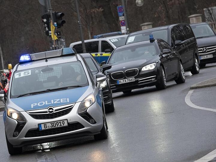 Ein Fahrzeug-Konvoi fährt unter Polizeischutz am Brandenburger Tor vorbei.