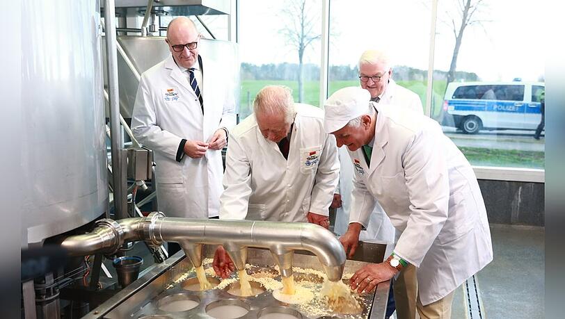 König Charles III. (2.v.l.) und Bundespräsident Frank-Walter Steinmeier (hinten) machen Käse in einem Ökodorf.