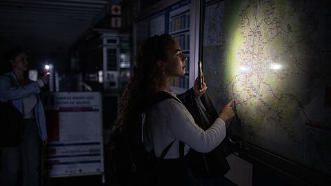 Eine Frau behilft sich mit der Taschenlampe ihres Handys, um den Plan des Madrider U-Bahn-Netzes anschauen zu können.