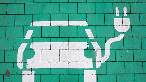 Ein Elektroauto auf grünem Grund markiert einen Parkplatz für Elektrofahrzeuge.