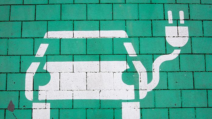 Ein Elektroauto auf grünem Grund markiert einen Parkplatz für Elektrofahrzeuge.