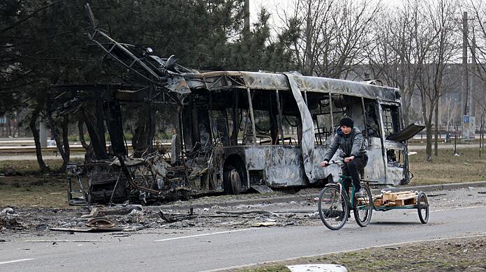 Eine Frau radelt nach Kämpfen am Stadtrand von Mariupol in einem Gebiet, das sich unter der Kontrolle der separatistischen Regierung der Volksrepublik Donezk befindet.