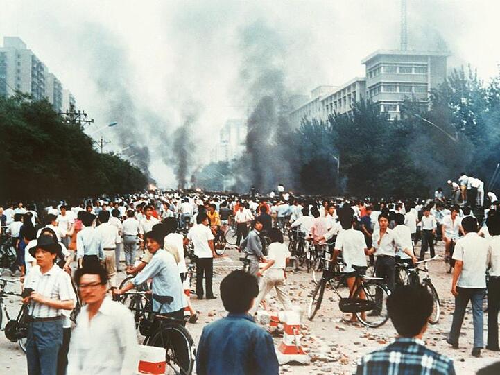 Rauchsäulen, Verwüstung und ratlose Menschen am 4. Juni 1989 auf der Changan Avenue in Peking.