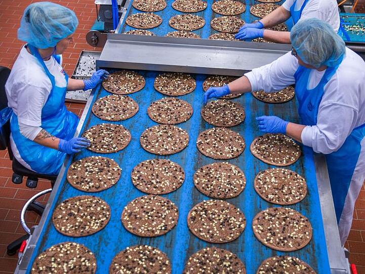 Mitarbeiterinnen belegen im Pizzawerk der Firma Dr. Oetker kakaohaltige Pizzaböden mit Schokoladensplittern. Die Schokoladenpizza wird nach zwei Jahren eingestellt.