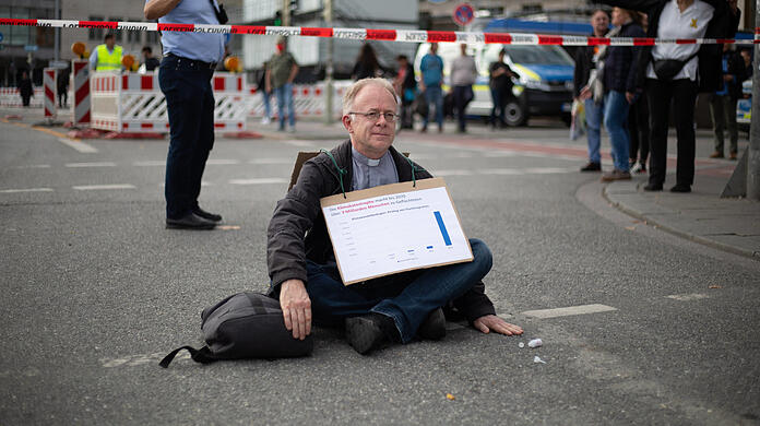 Jesuitenpater Jörg Alt bei seinem Klebeprotest am Stachus im Oktober 2022.