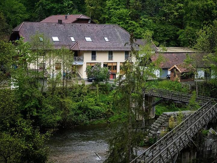Eine Pension steht von Bäumen umgeben an der Ilz in Paasau. Drei tote Personen sind dort in einem Zimmer gefunden worden.