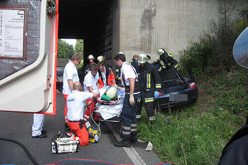 Die Feuerwehr hat den Porsche-Fahrer aus dem Wrack befreit, Sanitäter stehen zum Kliniktransport bereit.