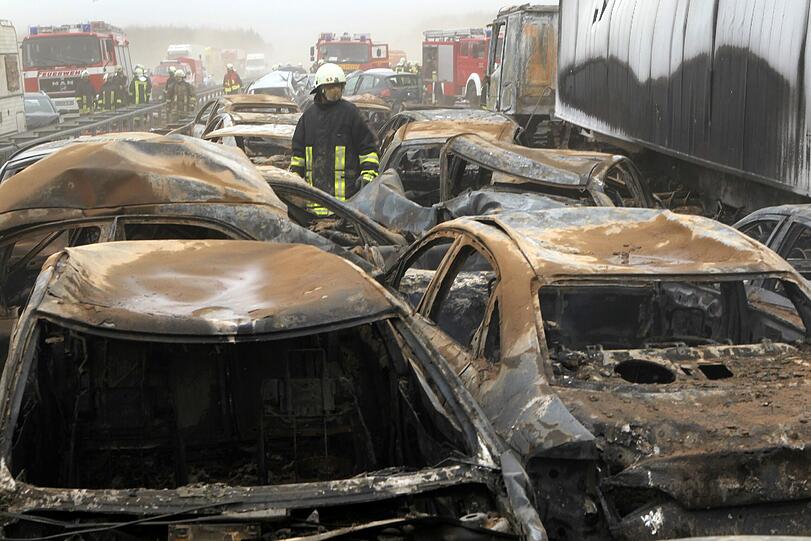 Feuerwehrleute sind am Freitag auf der Autobahn A19 bei Kavelstorf in der Nähe von Rostock bei einer Massenkarambolage im Einsatz. Bei einem Sandsturm fuhren in beiden Fahrtrichtungen Dutzende Fahrzeuge und LKW ineinander und brannten teilweise aus.
