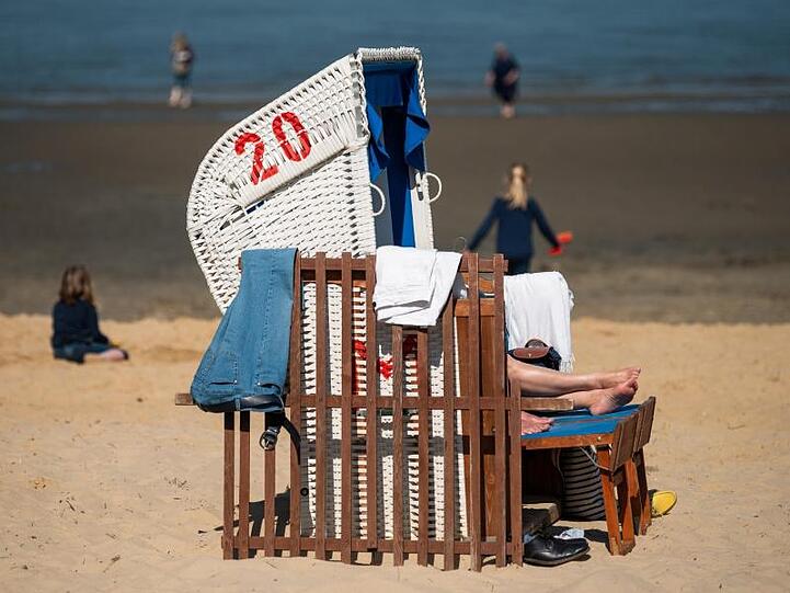 Strandbesucher liegen in Cuxhaven in der Sonne.