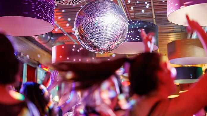 Publikum tanzt in Disco. Symbolbild