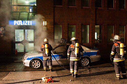 Feuerwehrleute löschen in Hamburg ein brennendes Polizeiauto Foto: dpa