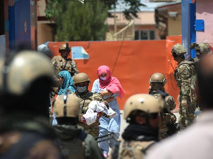 Sicherheitskräfte und Gesundheitspersonal mit Schutzmasken tragen Babys aus einem Krankenhaus nach einem Anschlag in Kabul.