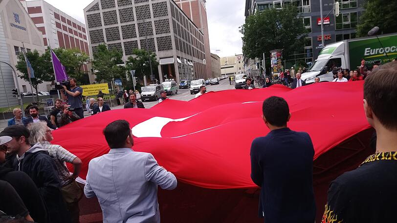 Demonstranten breiten vor dem Gerichtsgebäude eine Türkei-Flagge auf.